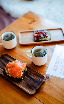 Matcha tea, salmon toast, and fruit tart on a wood table