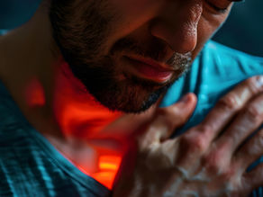 Man with a pained expression holds his chest, wearing a blue shirt. Red highlight on chest area, conveying discomfort or emphasis.