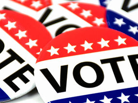 Red, white, and blue buttons with stars and the word "VOTE" overlap, conveying a patriotic and civic duty theme.