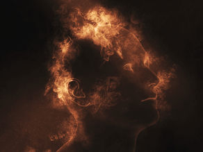 Silhouette of a human head formed by swirling orange flames on a dark background, creating an ethereal and intense atmosphere.