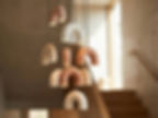 Cluster of Macaroni ceramic arch pendant lights beside a brick wall in staircase