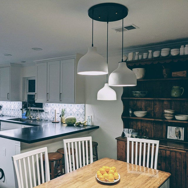 Three white pendant lights through single mulitport wooden canopy over long dining table