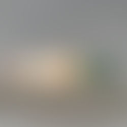 A row of five custom handmade ceramic color samples sitting on a grey textured surface. The samples range from tans and creams to various shades of green, demonstrating a custom color palette created to match specific Sherwin Williams paint codes.