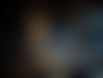 Modern living room with a warm-glow Naaya Bean ceramic wall sconce illuminating a dark textured wall, creating a cozy and elegant ambiance