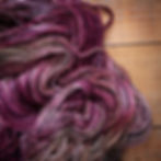 An unwound skein of Zebra yarn with a twist of black wound through it. Shades of purple and cream run throughout.