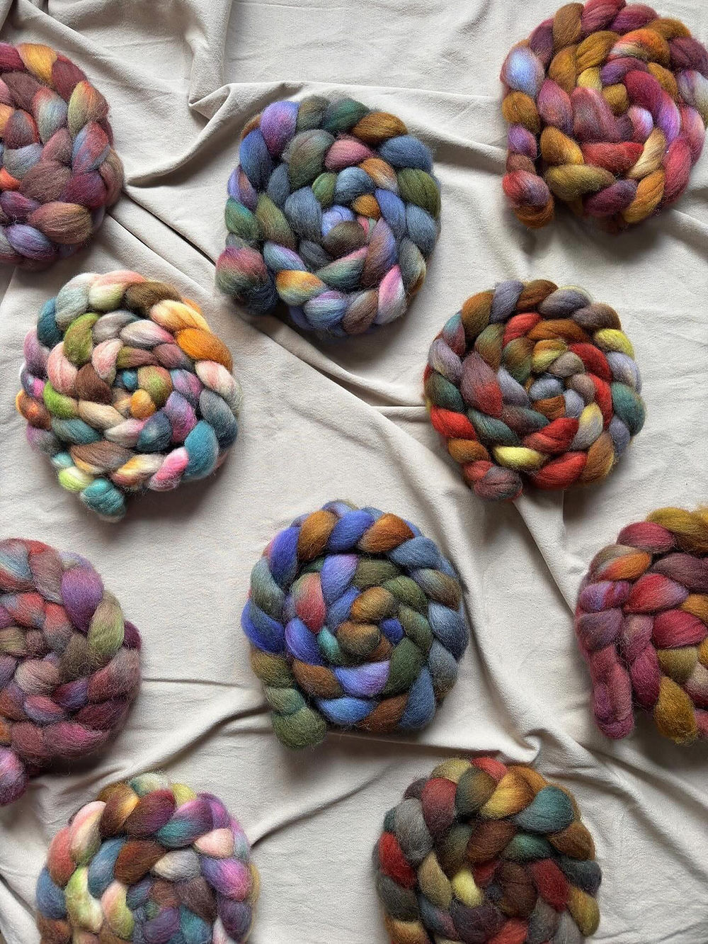 Ten coils of roving yarn in multi-colours arranged on a beige background