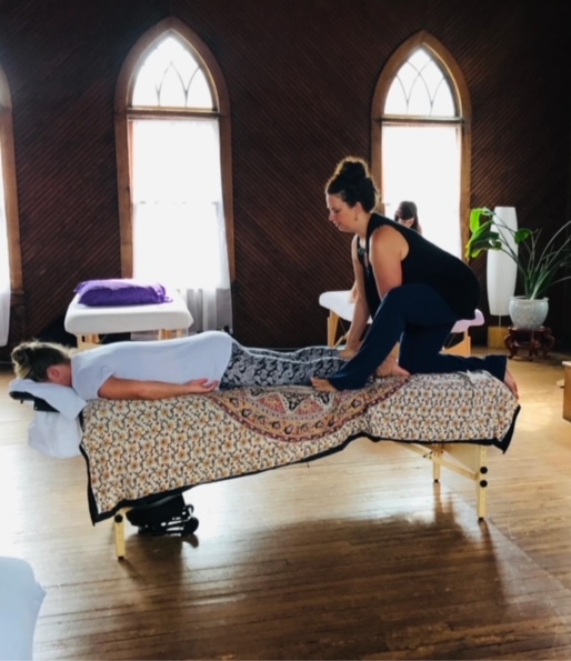 A person performing a gentle, assisted stretch on another, demonstrating flexibility and mindful movement in a wellness session.