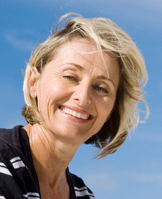 A picture of a smiling woman in front of a blue sky.