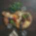 arial view of dark wooden table with greenery and large charcuterie board and water glasse