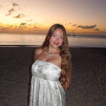 Jules Anderson standing on a beach in a silver floral maxi dress at sunset