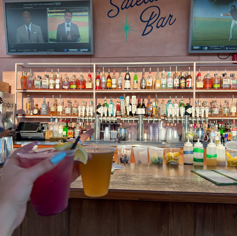 a rooftop bar with two drinks and a pink wall