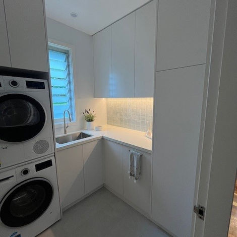 Modern laundry room with stacked washer, dryer, and sink