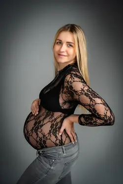 Těhotenské focení Ostrava – poloportrét těhotné ženy v krajkovém body na šedém pozadí. Jemné a elega