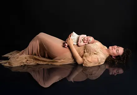 Originální těhotenské fotky - maminka ležící na zemi, na sobě má spící miminko a v odrazu na podlaze je ještě těhotná. 