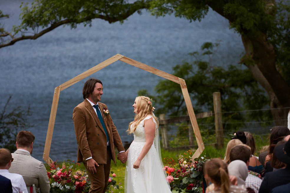 A bride and groom stood infront of a wedding arch.