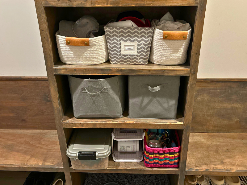 Mudroom shelving with labeled baskets for family storage, plus a lower shelf for pet food and water bowls. Entryway and pet station by Home Again Organizing.