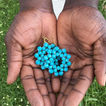 mano sosteniendo aretes con cuentas de estrellas azules brillantes diseñados por artesanos de _la tribu_