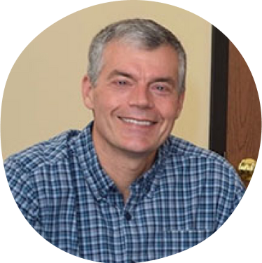 Jeffrey Cook, Executive Committee Member, smiling and wearing a blue patterned button down shirt