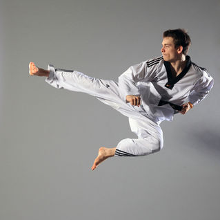 a man in a taekwondo uniform is kicking in the air
