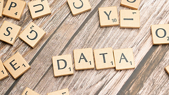 Scrabble-style tiles spell DATA on a wood surface, with scattered letter tiles around it.