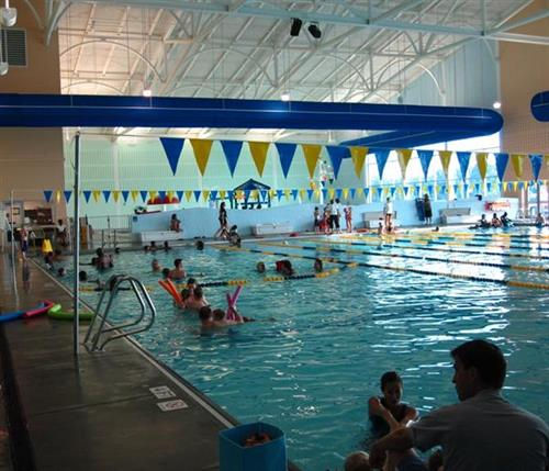 Families enjoy a day of swimming and fun at the bustling indoor pool of SRAC, complete with lane markers and colorful flags.