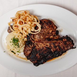 Porterhouse steak on plate with friend onions and mashed potatoes