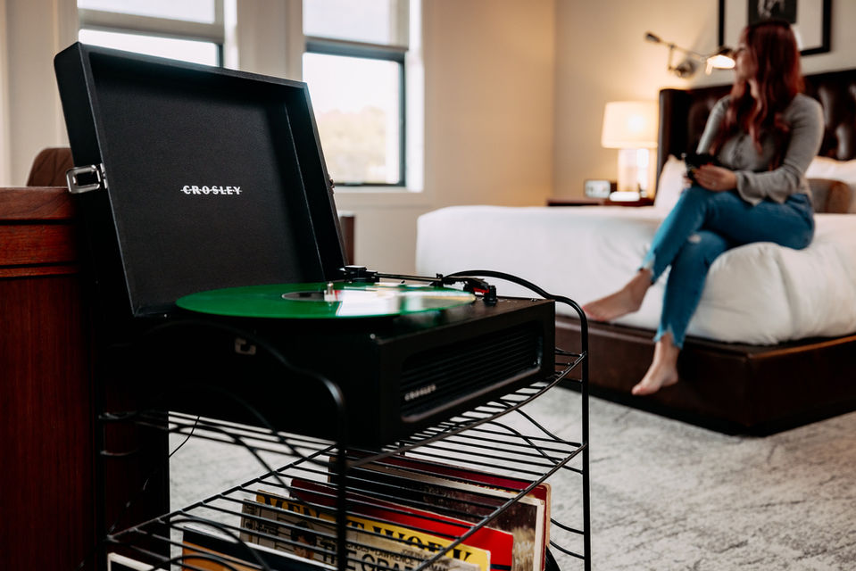 record player with woman sitting on bed in background