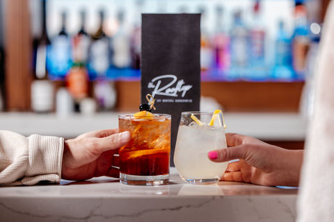 Two drinks cheersing in front of drink menu