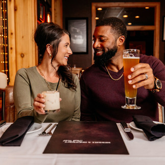 couple with cocktails sitting at table looking at menu.