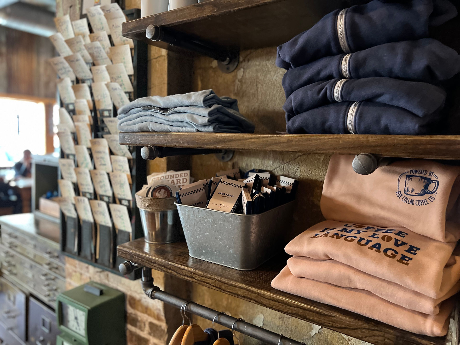 Image of several merchandise items for Blue Collar Coffee sitting on a shelf inside the shop.