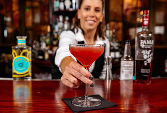 Bartender handing over pink cocktail on bar