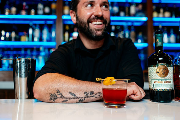 Bartender with cocktail in front of his arm.