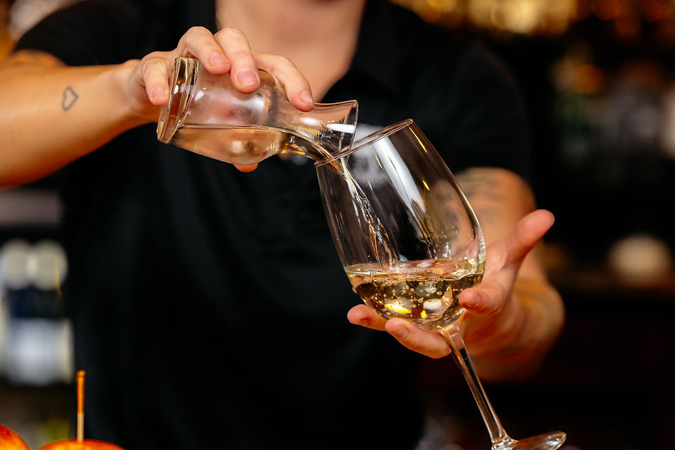 bartender pouring a glass of white wine into glass