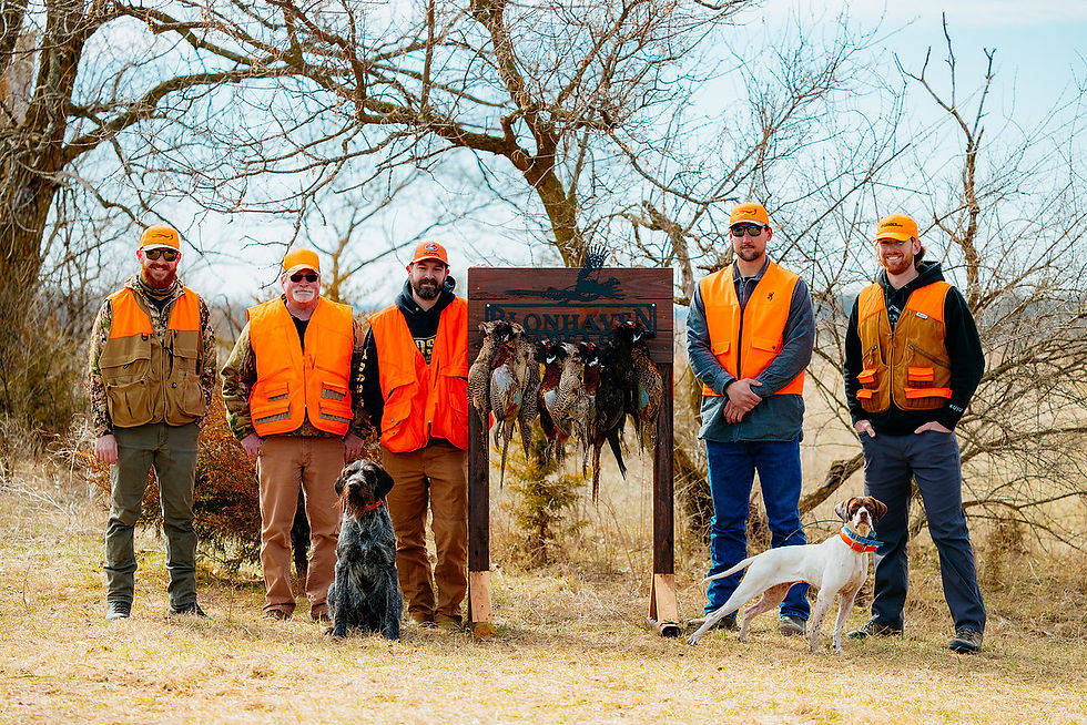 Group of 5 men standing next to sign holding up pheasants shot during a hunt.