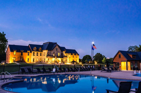 View of clubhouse lit up from pool at night 