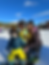 Two children in ski gear and a woman pose on a snowy slope with a mountain backdrop. The kids are smiling, evoking a joyful mood.