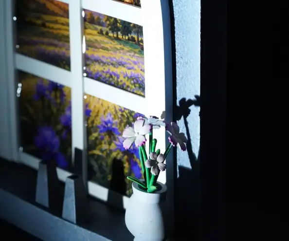 Un vase avec un bouquet de fleurs et un paysage au travers d'une fenêtre, figurines en résine peintes à la main