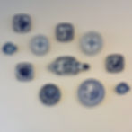 Blue and white decorative plates and fish-shaped ceramics with intricate patterns arranged on a plain wall.