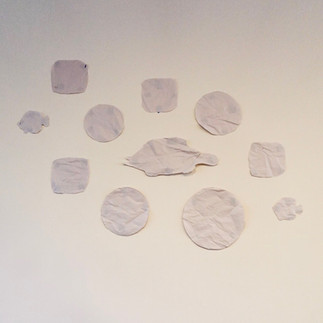 Paper templates taped in a decorative arrangement on a wall, creating a visual layout plan before drilling holes and hanging nails.