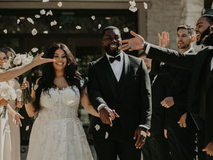 couple exiting their ceremony with flower petals being thrown by the crowd