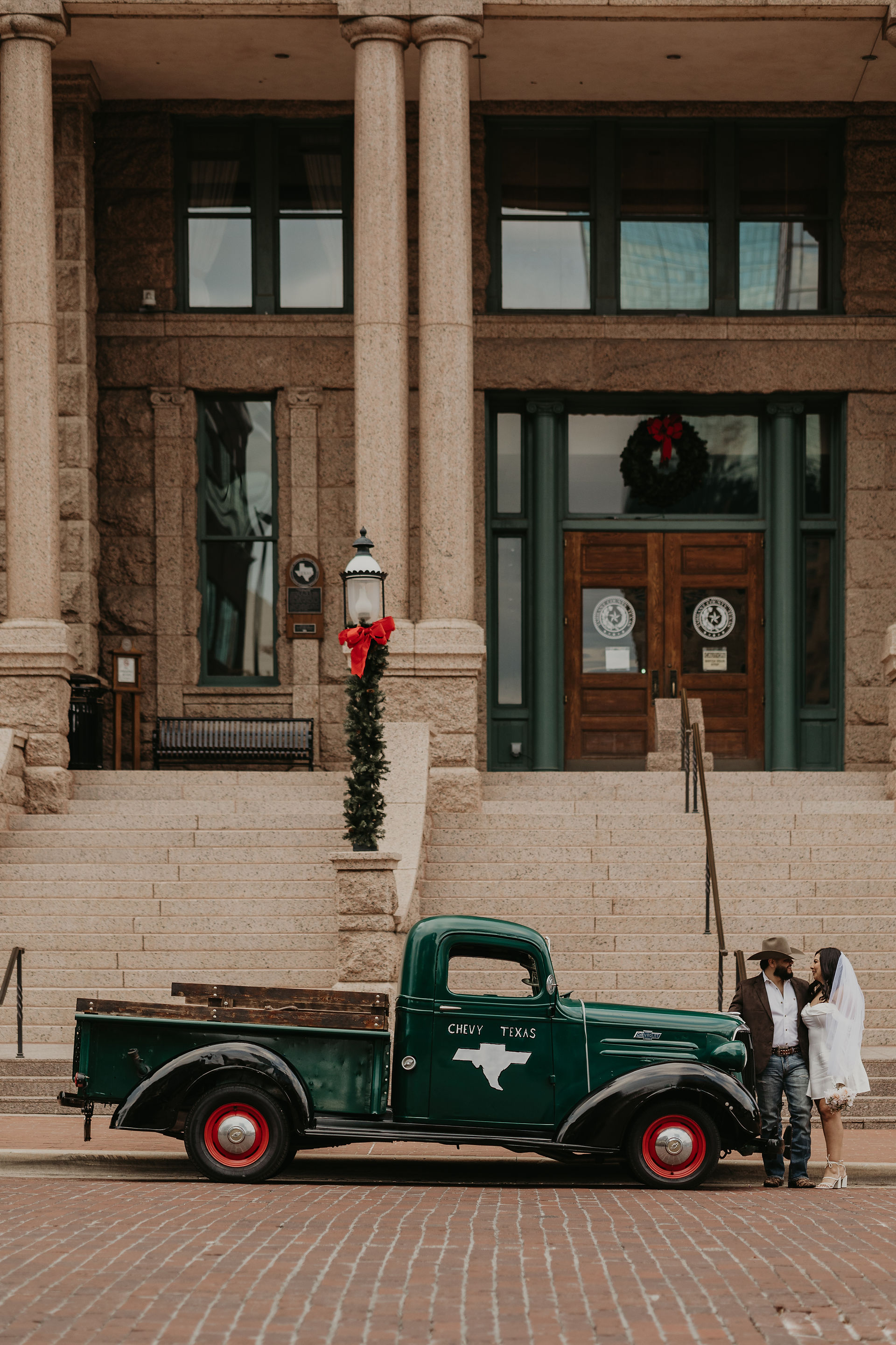 Classic engagement photo with vintage green pickup at historic Dallas courthouse — timeless city love stories captured