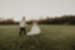 Bride and groom walk hand in hand across a sunset field during their elegant outdoor wedding in Texas, captured in a timeless, cinematic style.