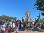 A large crowd in front of Cinderella's Castle at the Magic Kingdom on a sunny day.