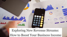 Person points at printed graphs with a pen, next to a smartphone calculator on a desk. Blue and red bars, charts, and calendar visible.