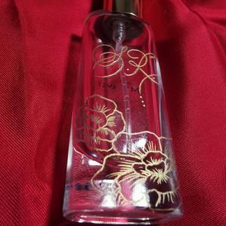 A clear perfume bottle hand engraved with a monogram and stylish florals
