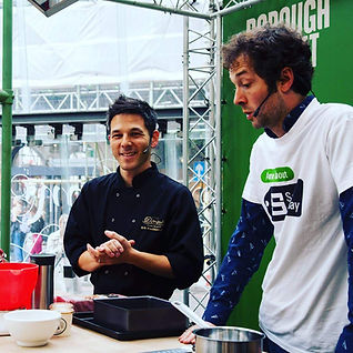 Erik Houlihan-Jong presenting a cookery demonstration at Borough Market as a Divine Chocolateer with presenter Chris Addison.