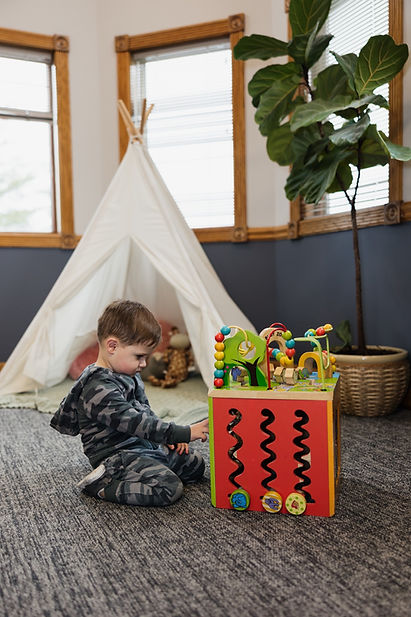 Young boy playing calmly with activity cube in the kid-friendly space of Vera Chiropractic.