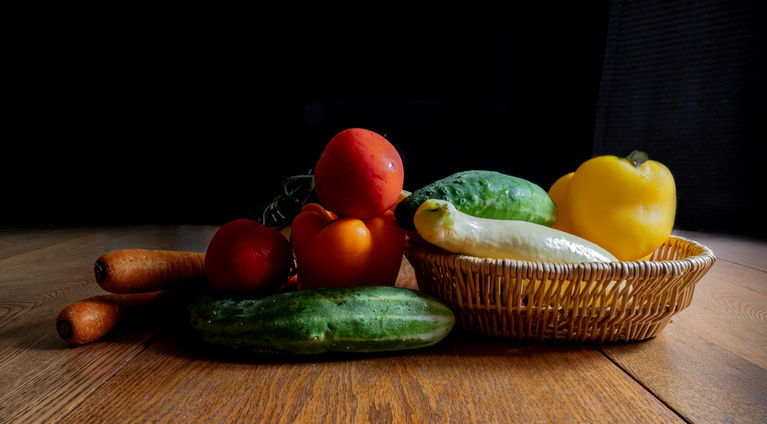 photo of various vegetables in basket against dark background