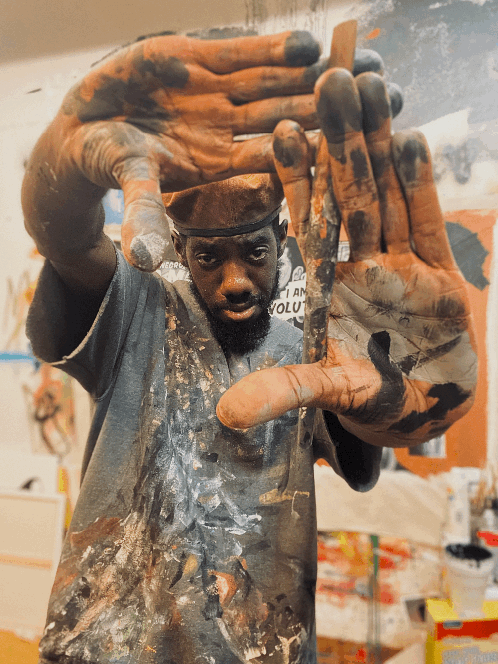 Image of a man covered in paint making a square viewer with his hands.