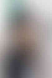 5. Senior portrait in cap and gown smiling near white wall